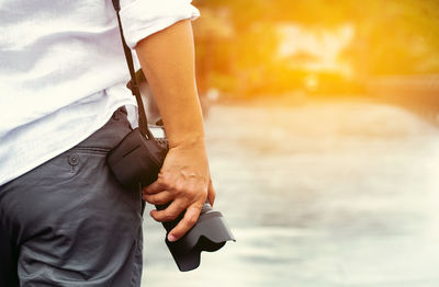 Midsection of man with camera outdoors