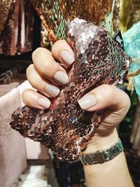 Cropped hand of woman holding sequin purse at store