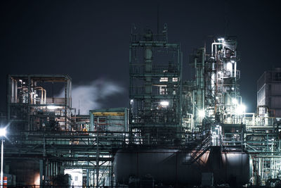 Illuminated factory against sky at night