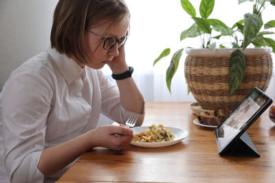Girl eats lunch with tablet