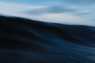 Powerful foamy sea waves rolling and splashing over water surface against cloudy blue sky