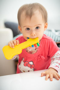 Portrait of cute baby girl sitting with toy