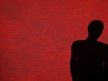 Rear view of silhouette man against red wall