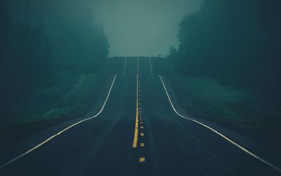 Road amidst trees during winter at night