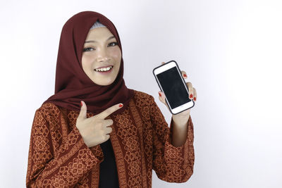 Portrait of smiling young woman using smart phone against white background