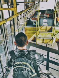 Rear view of backpack man standing in bus