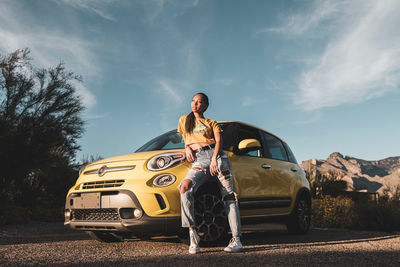 Man standing by car against sky