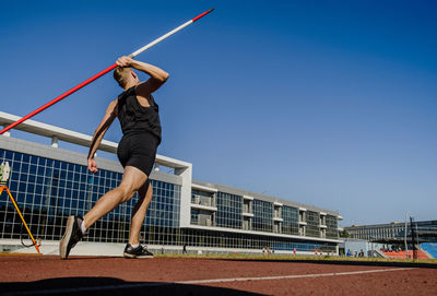 Woman with umbrella against clear blue sky