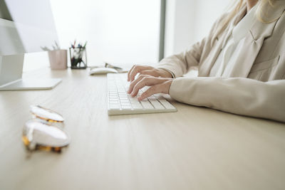 Close-up of businesswoman typing on computer keyboard