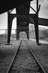 Bridge over railroad tracks against sky