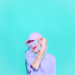 Laughing woman wearing cap standing against colored background