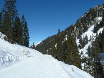 Snow covered landscape against clear blue sky