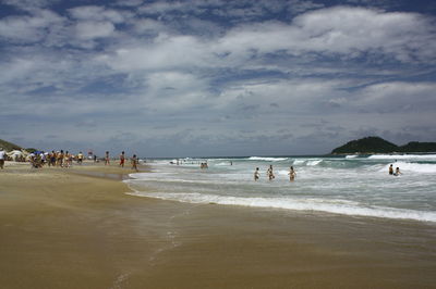 Group of people on beach against sky