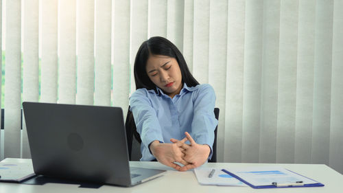 Young woman using mobile phone while sitting on table