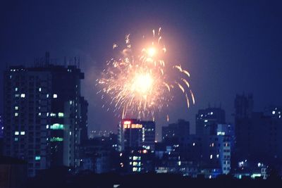 Firework display over illuminated buildings in city at night