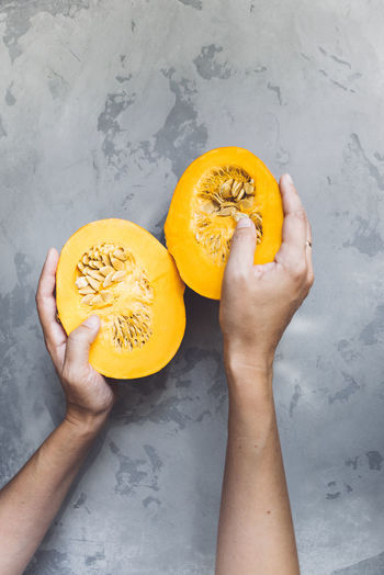 Close-up of female hand holding two halves of pumpkin