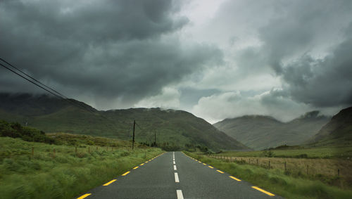 Road leading towards mountains against sky