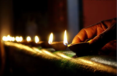 Cropped hand arranging lit diya at night