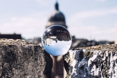 Close-up of crystal ball with reflection on umbrella against sky