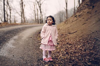 Portrait of girl standing on bare tree