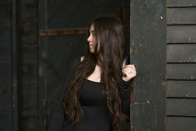 Portrait of young woman standing against wall