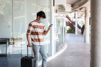 Man wearing mask using mobile phone outdoors