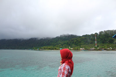 Rear view of girl with red outfit against sky