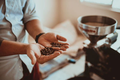 Midsection of man holding coffee beans while standing in shop