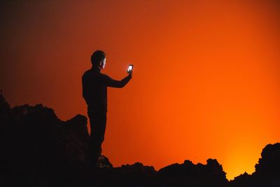 Silhouette of man standing against orange sky