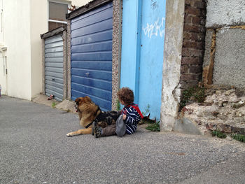 Rear view of two people sitting on wall