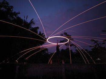 Light trails on bridge against sky at night