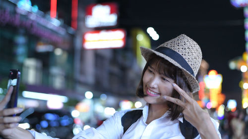 Portrait of smiling young woman in illuminated city at night