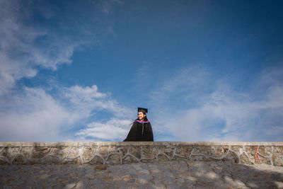 Woman standing on wall against sky