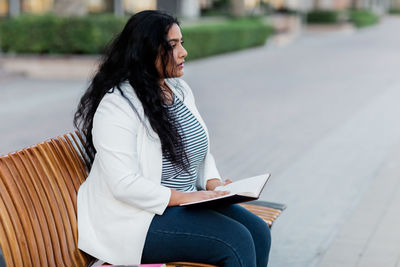 A beautiful girl is sitting on a bench and reading a book. the concept of urban lifestyle