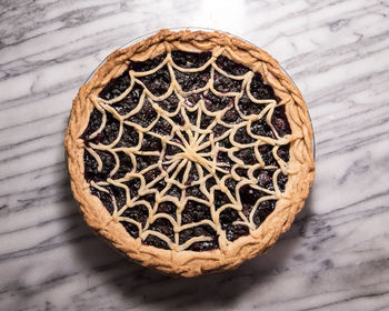 Blueberry pie with spiderweb lattice crust on marble pastry board