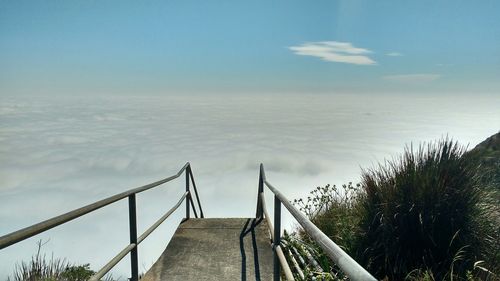 Staircase by cloudscape against sky