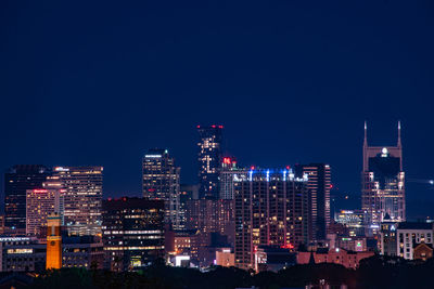 Illuminated buildings against clear sky at night