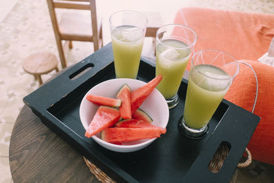 High angle view of drinks and watermelon slices served on table