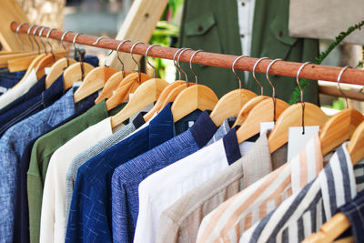 Wooden clothes racks with colorful male suits on hangers. showcase with clothes on street market.