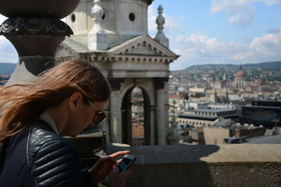 Side view of woman using mobile in balcony at st stephen basilica