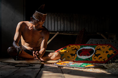 Full length of shirtless man sitting