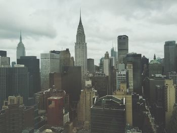 Skyscrapers in city against cloudy sky