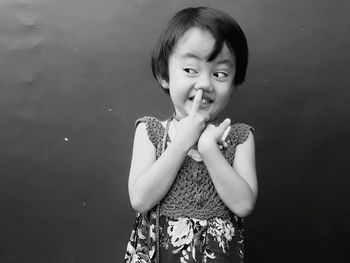 Mischievous girl picking nose against wall