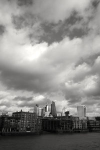 City at waterfront against cloudy sky