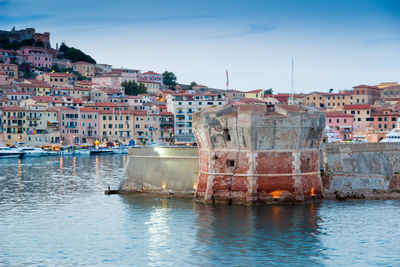 Buildings by sea against sky in city