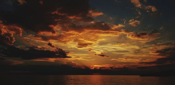 Scenic view of sea against dramatic sky during sunset