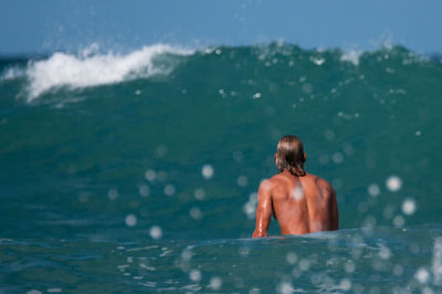 Rear view of shirtless man in sea