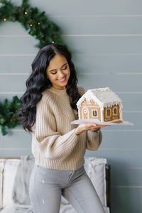 A pretty brunette holds a gingerbread house prepared with her own hands for christmas and admires