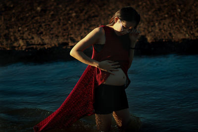 Pregnant woman standing against lake
