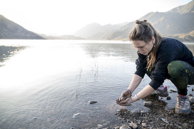 Woman putting mud on hands and face while enjoying outdoors in nature.